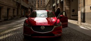 A woman exiting the driver side of a parked red 2020 Mazda6. | Mazda dealer in St. Louis, MO