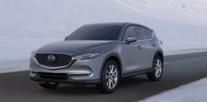 A silver 2020 Mazda CX-5 parked on a road with  snow on  the sides of the road and in the background. | Mazda dealer in St. Louis, MO