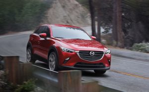 A red 2020 Mazda CX-3 being driven on the highway in a forested area. | Mazda Dealer in St. Louis, MO