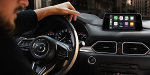 Angles view of a man and his hand resting on the steering wheel of a 2020 Mazda CX-5. | Mazda dealer in St. Louis, MO