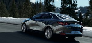 A dark gray 2021 Mazda3 Sedan being driven on the highway with trees in the background. | Mazda dealer in St. Louis, MO