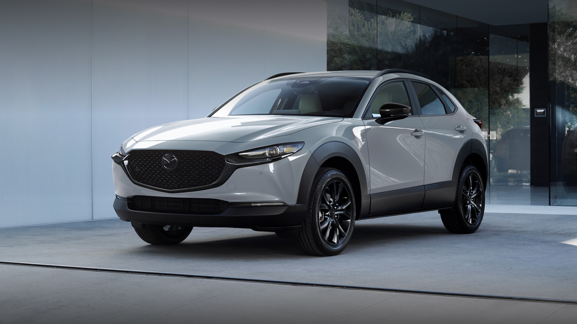 2026 Mazda CX-30 compact SUV in white displayed in a modern showroom, featuring sleek styling, a black grille, and clean architectural surroundings in St. Louis, Missouri.